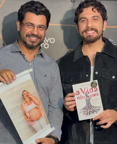 Gledson Fonseca e Gustavo Mioto; Mioto segura o livro A Vida Não Para.