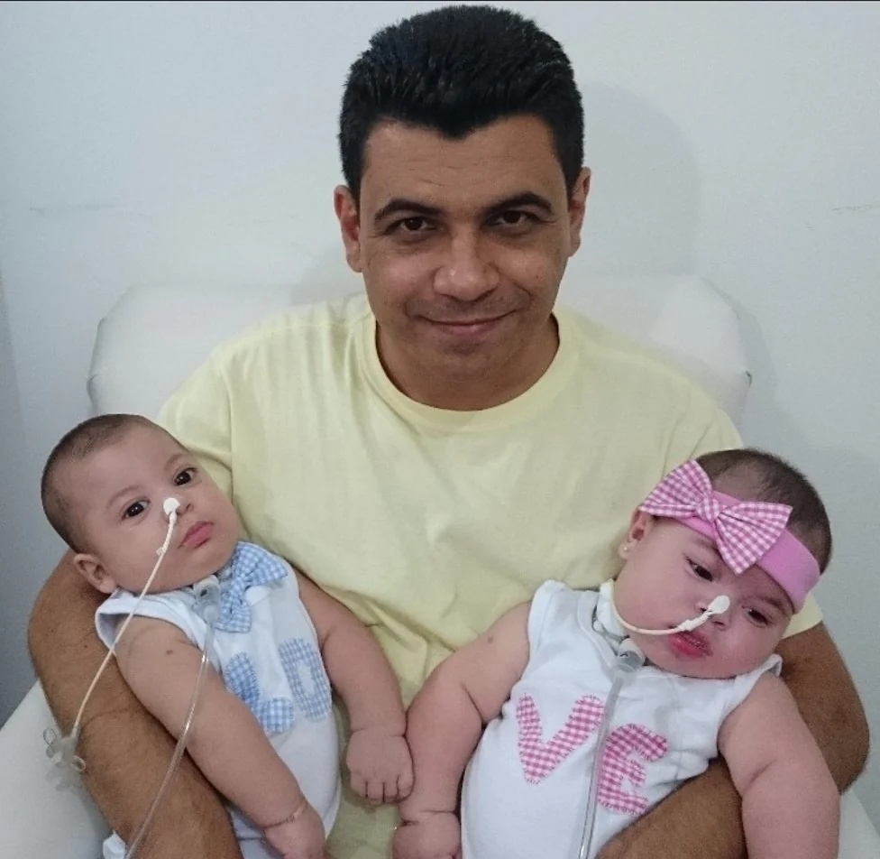 Gledson com os dois bebês no colo.